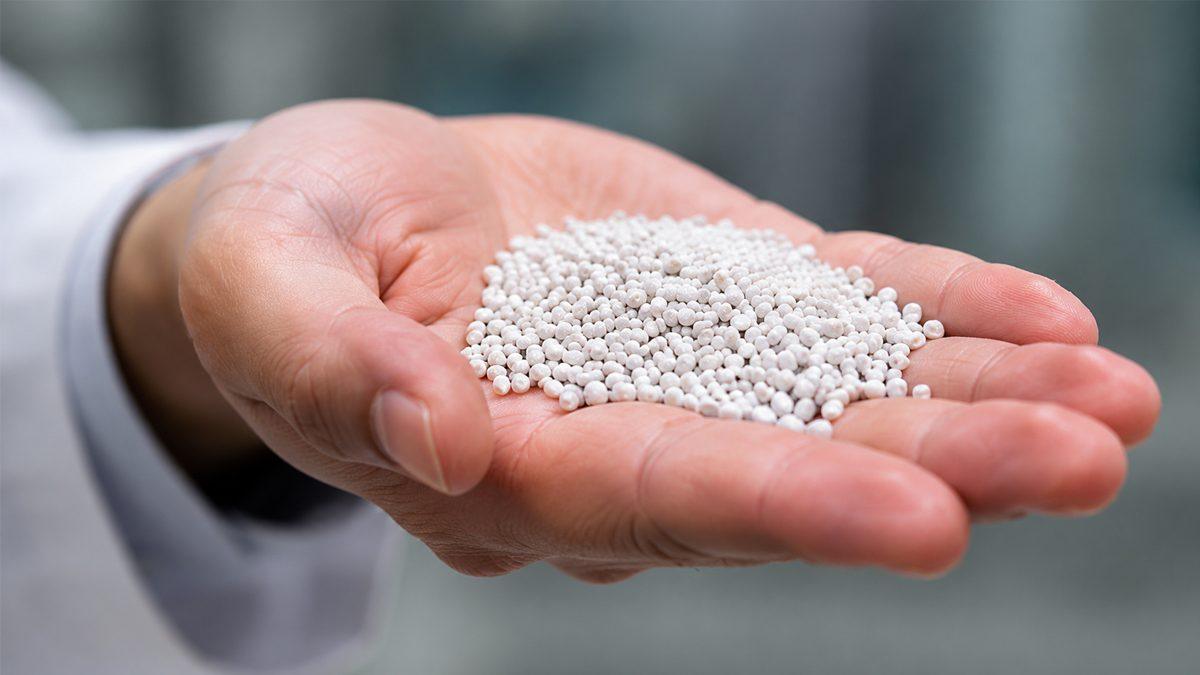 High-performance polymer pellets held in hand, representing AM Solution's scalable molecular engineering materials